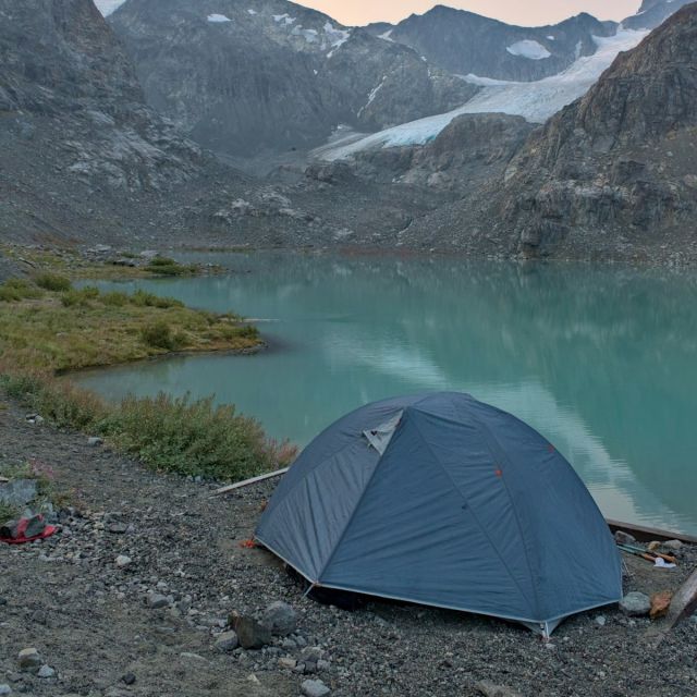 Tent beside a glacial lake below hanging glaciers
