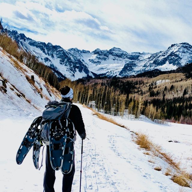 Hiker carrying snowshoes on the Alpine 55L across a snowfield